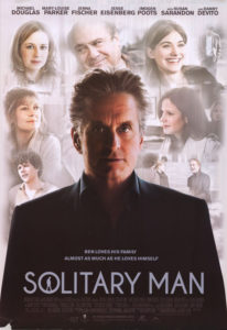 Michael Douglas stands alone with other actors are fuzzy in the background on the poster for the movie Solitary Man