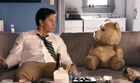 Mark Wahlberg and Ted sitting on a couch looking at each other in the film Ted