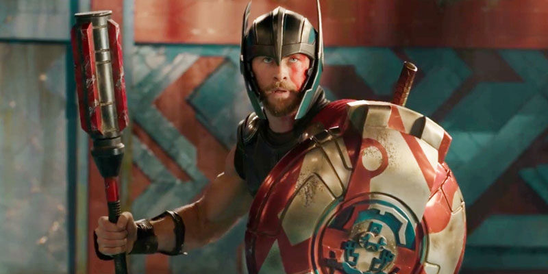 Chris Hemsworth in Thor: Ragnarok holding a shield and a weapon with a helmet on, ready for battle.