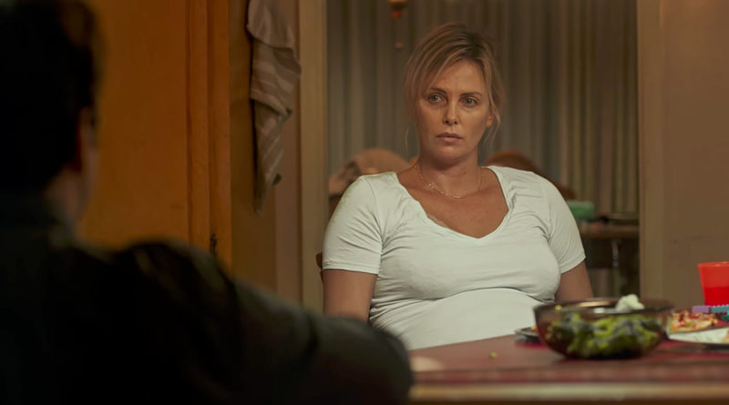 Charlize Theron looking exhausted sitting at a table in Tully.