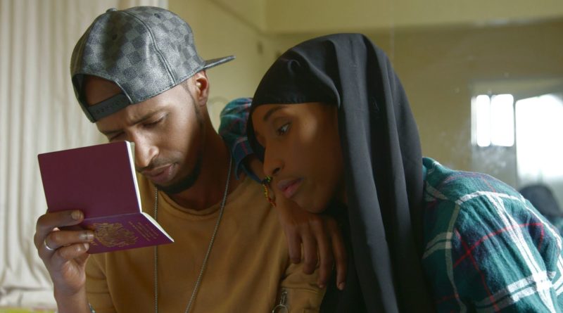 Mohammed and Fahti a Somali couple in the documentary Lost Warrior stare at a passport intently as Fahti leans on Mohammed.