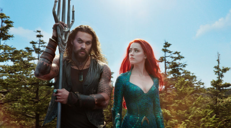 Jason Mamoa leaning on his trident and Amber Heard looking intently to him on the left in the movie Aquaman