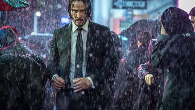 Keanu Reeves walks alone in a crowd in the rain in John Wick: Chapter 3