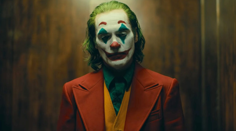 Joaquin Phoenix wearing his clown makeup in a suit looking serious in the movie Joker