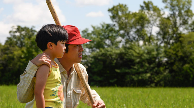 Steven Yeun crouches with his arm around Alan S. Kim in the movie Minari