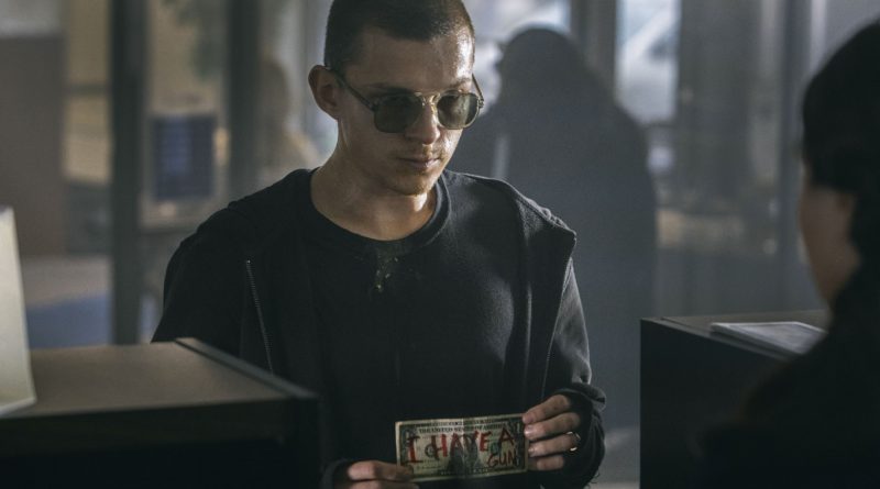 Tom Holland wears sunglasses and presents a dollar bill saying he has a gun in the movie Cherry