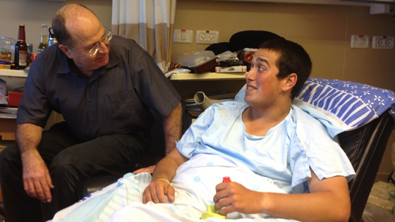 Wounded soldier Uri sits in a hospital chair talking to an older man in the documentary short Image of Victory.